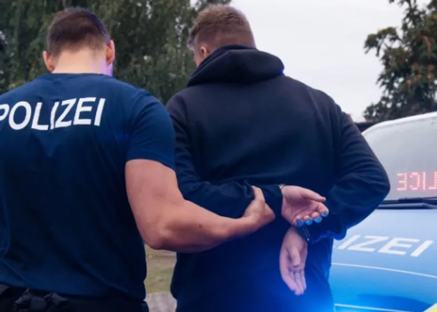 Polizist nimmt eine Person fest, die Hände auf dem Rücken gefesselt