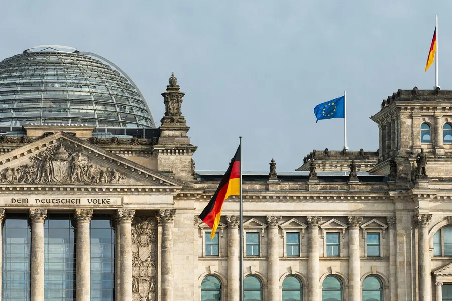 Reichstagsgebäude in Berlin mit wehenden deutschen und EU-Flaggen